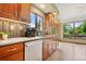 A kitchen sink area features stainless steel appliances, light countertops and custom cabinets under a large sunny window at 6307 S Gallup St, Littleton, CO 80120