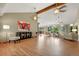 Open-concept living room with hardwood floors, beamed vaulted ceiling, and seamless transition to dining area at 6307 S Gallup St, Littleton, CO 80120