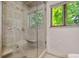 Shower with tile surround, glass door, bench, and a window at 6307 S Gallup St, Littleton, CO 80120
