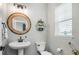 Stylish powder room features a pedestal sink, modern lighting, and a round decorative mirror at 2028 Trail Stone Ct, Castle Rock, CO 80108