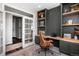 Elegant home office featuring built-in shelves, a wood desk, a modern chair, and ample natural light at 2028 Trail Stone Ct, Castle Rock, CO 80108