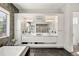 Bathroom featuring dual sinks, white cabinets, a decorative mirror, and marble floors at 42 S Ash St, Denver, CO 80246