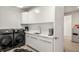 Modern laundry room with sleek white cabinets, a sink, and a high-end washer and dryer at 42 S Ash St, Denver, CO 80246
