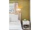 Bright bedroom with decorative olive wallpaper and white, cozy bedding with a wicker headboard and a white nightstand at 11223 W 29Th Ave, Lakewood, CO 80215