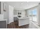 Bright kitchen features gray cabinets, stainless appliances, and a center island with snow outside the sliding glass door at 5784 Farmstead Pl, Mead, CO 80504