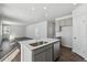 Open floor plan with kitchen island and gray cabinets adjacent to large living room with wood-look floors at 5784 Farmstead Pl, Mead, CO 80504
