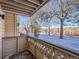 Balcony view of snow-covered grounds and trees with lattice railing at 400 Zang St # 1-105, Lakewood, CO 80228