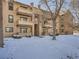Condominium exterior, showing balconies, snow covered lawn, and mature tree at 400 Zang St # 1-105, Lakewood, CO 80228