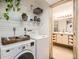 Bright laundry room leading into the bathroom with washer, dryer, storage shelves and hanging plants at 400 Zang St # 1-105, Lakewood, CO 80228