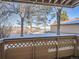 View of snow-covered grounds and trees from a patio with lattice railing at 400 Zang St # 1-105, Lakewood, CO 80228