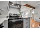 Kitchen with stainless steel range, light gray cabinetry, white countertop, and wood beam feature visible to living room at 201 Wright St # 105, Lakewood, CO 80228