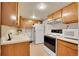 Basement kitchenette featuring wood cabinets, white appliances, and a sink at 8040 W 78Th Way, Arvada, CO 80005