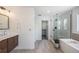 Modern bathroom featuring a glass-enclosed shower, soaking tub, and stylish vanity at 4180 Ames St, Denver, CO 80212