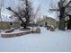 Snowy backyard with stone retaining walls and mature trees at 2561 W Dartmouth Ave, Denver, CO 80236