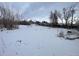 Large, snow-covered lot with mature trees, presenting a serene and private setting for building a dream home at 2561 W Dartmouth Ave, Denver, CO 80236