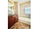 Well-lit bathroom featuring granite counters, tiled walls, and tub with shower at 2561 W Dartmouth Ave, Denver, CO 80236