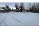 Wide shot of the lot showcasing its potential for development, with mature trees and a snowy landscape at 2561 W Dartmouth Ave, Denver, CO 80236