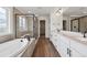 Bright bathroom featuring a soaking tub, a glass enclosed shower and double vanity with wood-style flooring at 24708 E 40Th Ave, Aurora, CO 80019