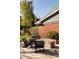 A gas fire pit area has a brick house wall, concrete planters and black Adirondack chairs at 26 Morningside Dr, Wheat Ridge, CO 80215