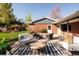 A patio area has a gas fire pit, outdoor seating, a brick house wall and a landscaped yard at 26 Morningside Dr, Wheat Ridge, CO 80215