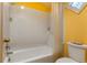 White tiled tub and shower combination with yellow walls and white fixtures at 400 S Steele St # 13, Denver, CO 80209