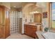 Serene bathroom with a glass-block shower, neutral tones, wood cabinets and a bright window view at 15533 S Perry Park Rd, Palmer Lake, CO 80133