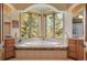 Bright bathroom featuring a soaking tub nestled between windows overlooking lush greenery, with tiled accents at 15533 S Perry Park Rd, Palmer Lake, CO 80133