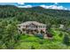 Stunning two-story home nestled on a picturesque hillside with lush landscaping and a charming split rail fence at 15533 S Perry Park Rd, Palmer Lake, CO 80133