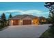 View of house with three-car garage, featuring stone accents and inviting front entry at 15533 S Perry Park Rd, Palmer Lake, CO 80133