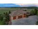 Wide view of home's driveway and three-car garage, landscaped for privacy at 15533 S Perry Park Rd, Palmer Lake, CO 80133