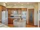 Well-lit kitchen with island, pantry, stainless steel appliances, and wood cabinets at 15533 S Perry Park Rd, Palmer Lake, CO 80133