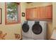 Bright laundry room featuring a washer and dryer, wooden cabinets, and a window with a nature view at 15533 S Perry Park Rd, Palmer Lake, CO 80133