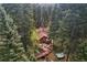 Aerial view of a wooded home with a large deck, outdoor seating, and a hot tub in a tranquil forest setting at 27802 Shadow Mountain Dr, Conifer, CO 80433