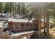 Inviting log cabin with a covered porch nestled among tall pine trees and snow at 27802 Shadow Mountain Dr, Conifer, CO 80433