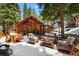 Outdoor patio with dining and seating areas surrounded by trees and snow at 27802 Shadow Mountain Dr, Conifer, CO 80433