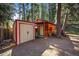 Outdoor storage shed with rustic charm, nestled beside a small cabin and surrounded by a lush, wooded landscape at 27802 Shadow Mountain Dr, Conifer, CO 80433