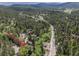 Elevated view highlights home's serene location and surrounding mountains, featuring road access and a verdant tree canopy at 4843 Silver Spruce Ln, Evergreen, CO 80439