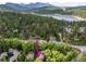 Aerial view capturing a mountain neighborhood with lush trees, and a serene lake with a home in the foreground at 4843 Silver Spruce Ln, Evergreen, CO 80439