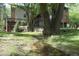 Scenic backyard view showcasing a gentle creek flowing through lush grass, framed by mature trees and a glimpse of the home at 4843 Silver Spruce Ln, Evergreen, CO 80439