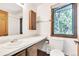 This bathroom features a large mirror, a wood-framed window and a functional layout at 4843 Silver Spruce Ln, Evergreen, CO 80439