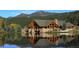 Picturesque log cabin home with stone foundation overlooking a serene lake, reflecting in the water at 4843 Silver Spruce Ln, Evergreen, CO 80439