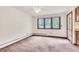 Bright, empty living room with carpeted floor and wooden trim around the windows and door at 4843 Silver Spruce Ln, Evergreen, CO 80439