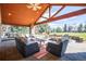 Large covered patio featuring comfortable seating, an outdoor fireplace, and scenic backyard views at 26 Wedge Way, Littleton, CO 80123