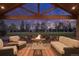 Covered outdoor living space with comfortable seating around a stone fire pit overlooking the backyard at 26 Wedge Way, Littleton, CO 80123