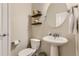 Cozy powder room featuring a pedestal sink, round mirror, and decorative shelving at 3120 Redhaven Way, Highlands Ranch, CO 80126