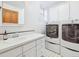 Bright laundry room with front-loading washer/dryer, white cabinets, and tiled floors at 5801 W 33Rd Ave, Wheat Ridge, CO 80212
