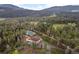 Aerial view of a house and outbuildings nestled in a forest with mountain views at 27987 Pine Grove Trl, Conifer, CO 80433