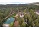 Aerial view of a house on a large lot with a green-roofed outbuilding surrounded by towering trees at 27987 Pine Grove Trl, Conifer, CO 80433