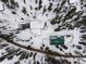 Aerial view showing the home's layout, circular drive, and the surrounding, snow-covered trees at 27987 Pine Grove Trl, Conifer, CO 80433