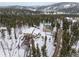 Aerial view showcasing the home, greenhouse, barn, and surrounding wooded landscape at 27987 Pine Grove Trl, Conifer, CO 80433